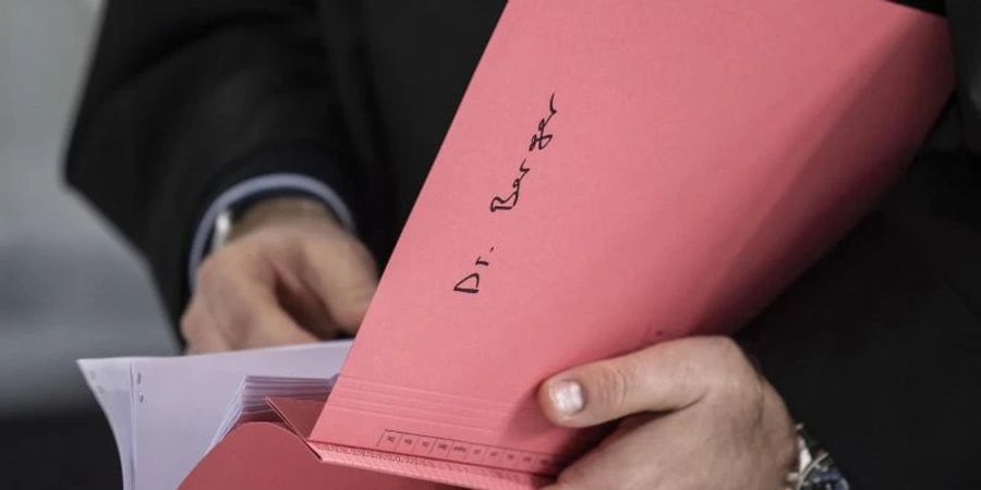 Ein Rechtsanwalt des Hauptbeschuldigten Hanno Berger hält vor dem Prozessauftakt um «Cum-Ex»-Aktiendeals im Gerichtssaal eine Akte mit der Aufschrift «Dr. Berger» in der Hand. Foto: Boris Roessler/dpa