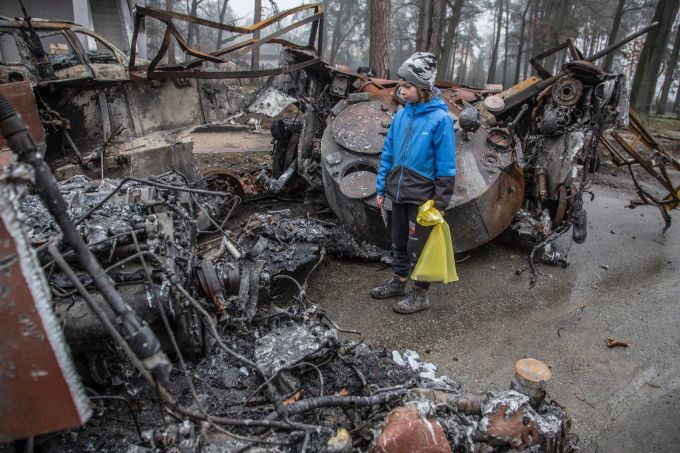 Ein ukrainischer Junge begutachtet die Überreste eines zerstörten Panzers im Ort Butscha nahe der Hauptstadt Kiew. Foto: Oleksandr Ratushniak Kriegskinder