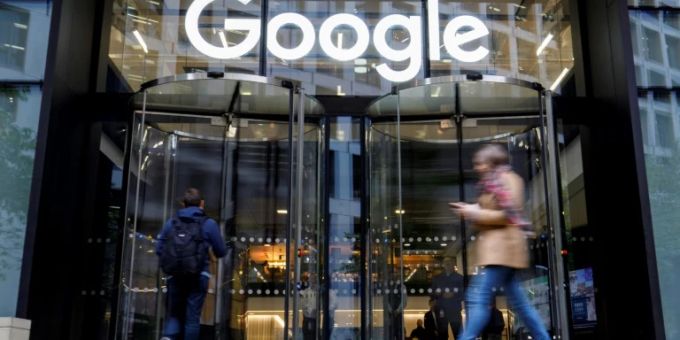 Menschen laufen an einem Google-Schriftzug vorbei. google
