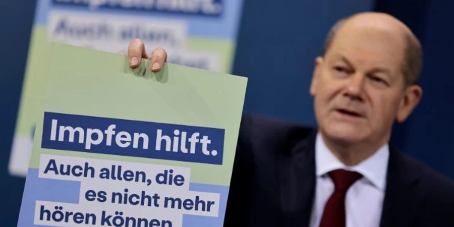 Kanzler Scholz zeigt Werbeplakat für Impfungen