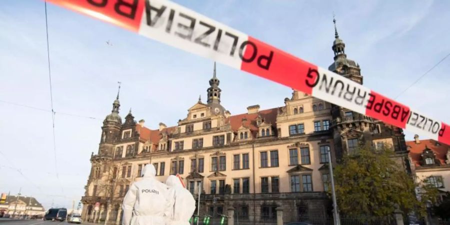 Zwei Mitarbeiter der Spurensicherung stehen vor dem Residenzschloss mit dem Grünen Gewölbe hinter einem Absperrband. Foto: Sebastian Kahnert/zb/dpa