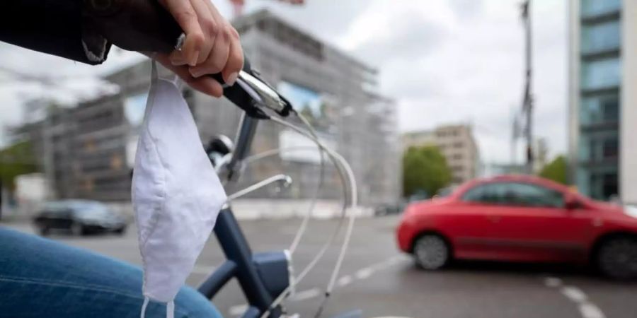 Eine Frau fährt mit Fahrrad und Mundschutz durch Stuttgart. Foto: Sebastian Gollnow/dpa