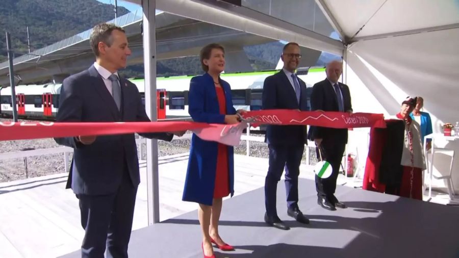 Im den Farben des Kantons Tessin gekleidet schneidet Bundespräsidentin Simonetta Sommaruga feierlich das Band zur Eröffnung des Ceneri-Basistunnels durch.