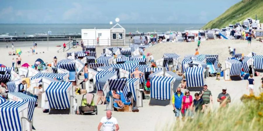 Urlaubsgäste sitzen bei sonnigem Wetter in ihren Strandkörben am Nordstrand der Insel Norderney. Foto: Hauke-Christian Dittrich/dpa