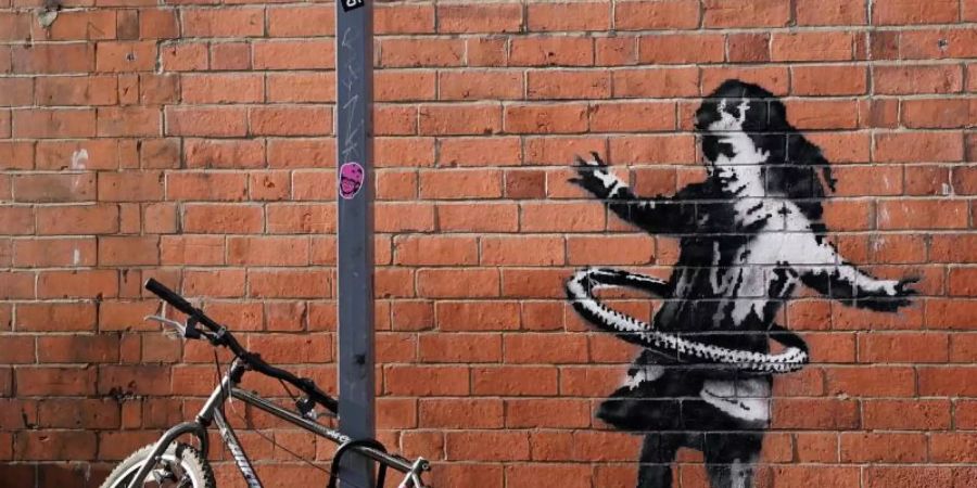 Das neueste Street-Art-Werk des britischen Künstlers Banksy auf einer Backsteinfassade in der Rothesay Avenue zeigt ein Mädchen, das mit einem Hula Hoop Reifen spielt. Foto: Tim Goode/PA Wire/dpa