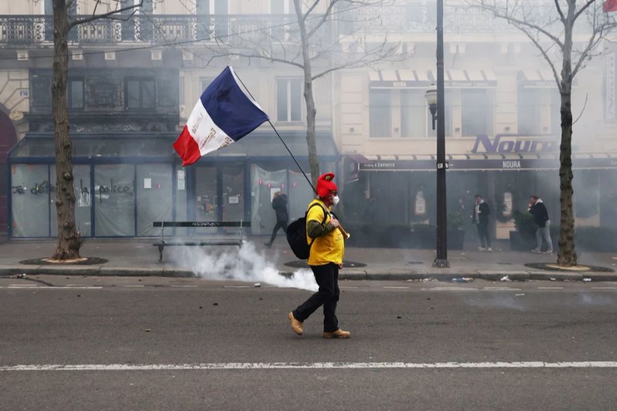 In Paris läuft ein Demonstrant mit einer französischen Flagge umher.