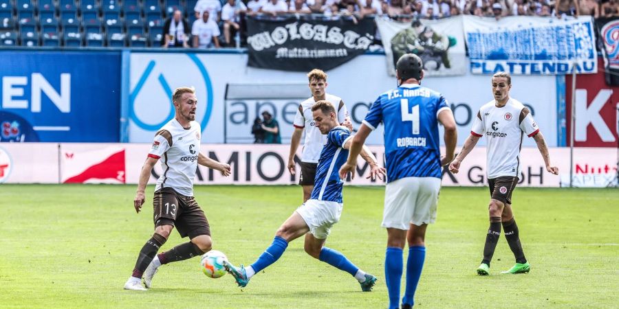 Rostocks Dennis Dressel (M) und St. Paulis Lukas Daschner ziehen im Zweikampf zum Ball.