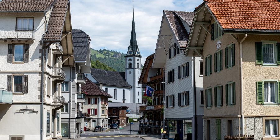 Die Dorfstrasse durch das Dorf Flühli und im Hintergrund die Römisch-Katholische Kirche St. Josef Flühli.