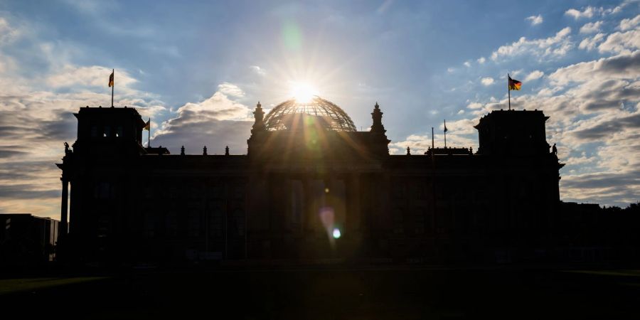 Über dem Reichstagsgebäude geht die Sonne auf.