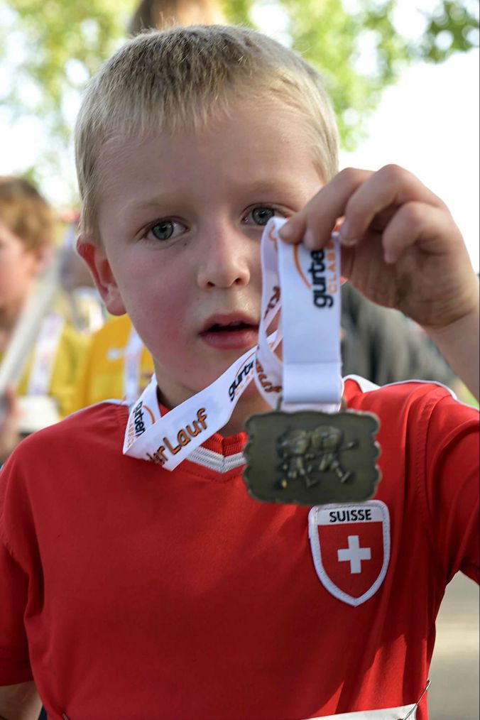 William präsentiert müde aber stolz seine Medaille.