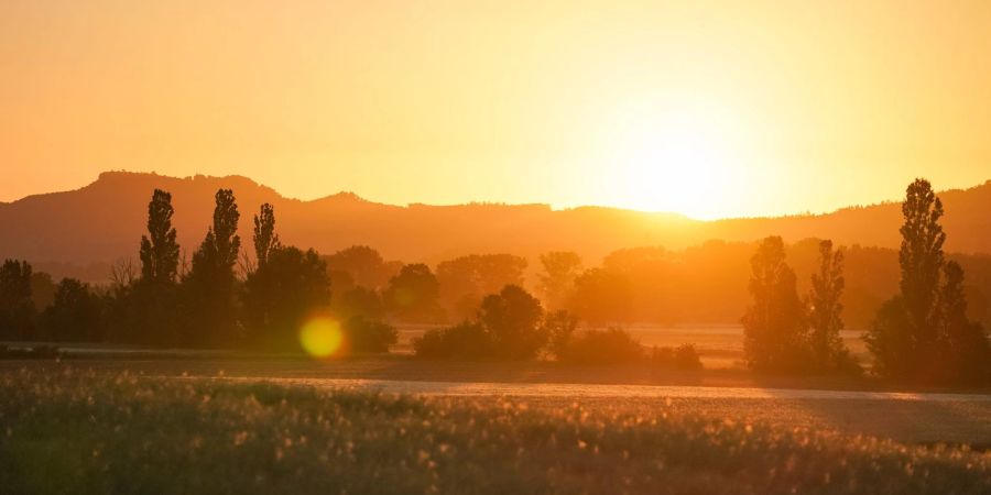 Die aufgehende Sonne lässt die umliegende Landschaft in einem orangefarbenen Licht aufleuchten. Auf der gesamten Nordhalbkugel ist es am 21. Juni am längsten hell.