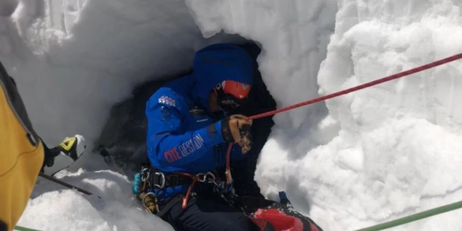 Ein Rettungsspezialist seilt sich zum verunfallten Skifahrer ab. Der Italiener brach durch die Schneedecke, fiel in den darunterliegenden Gletscherbach und wurde unter dem Schnee mehrere Meter talwärts gespült.