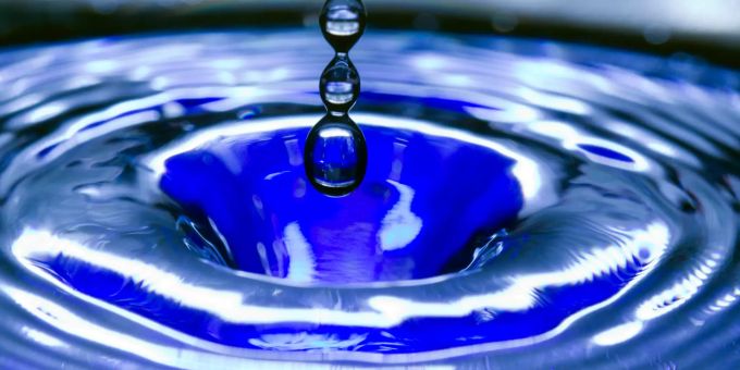 Ein Wassertropfen fällt in eine blaue Wasserschüssel. wagenhausen