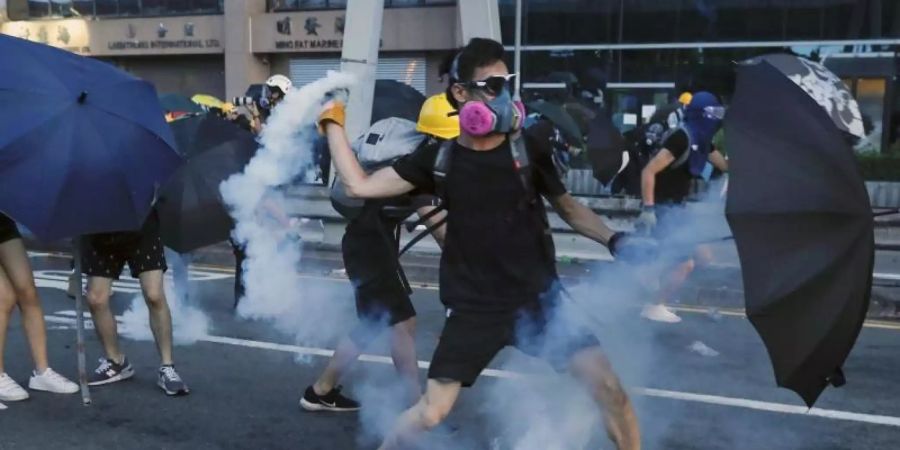 Ein Demonstrant wirft einen Tränengasbehälter, der von der Polizei abgefeuert wurde. Foto: Vincent Yu/AP