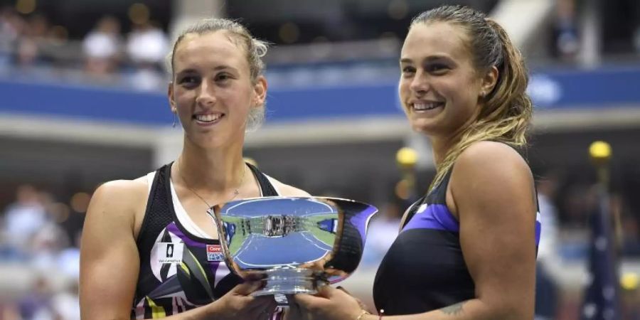 Aryna Sabalenka (r) und Elise Mertens halten nach ihrem Sieg im Doppel bei den US Open die Trophäe in den Händen. Foto: S. Stier/AP