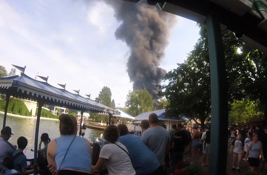 Besucherinnen und Besucher beobachten die dunkle Rauchsäule über dem Europa-Park Rust (D).