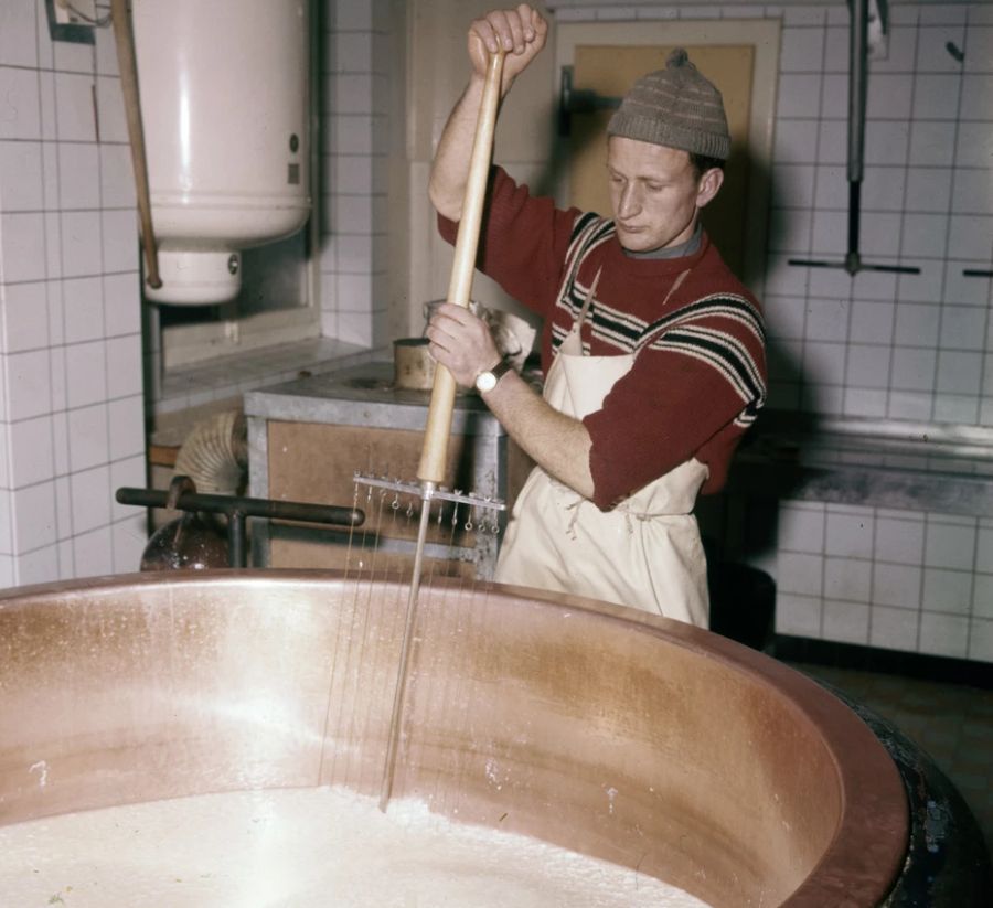 Grund für die Veränderung? Die Produktion hat sich weiterentwickelt. Hier rührt ein Arbeiter die Milch für den Käse von Hand (1959).