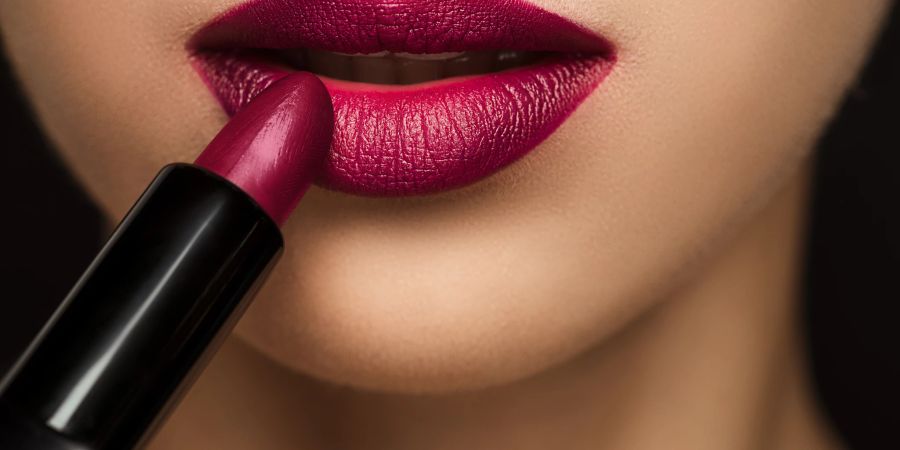 Frau trägt Lippenstift auf die Lippen auf