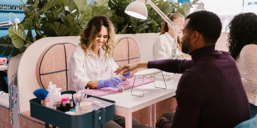 Nageldesignerin lackiert Mann die Fingernägel