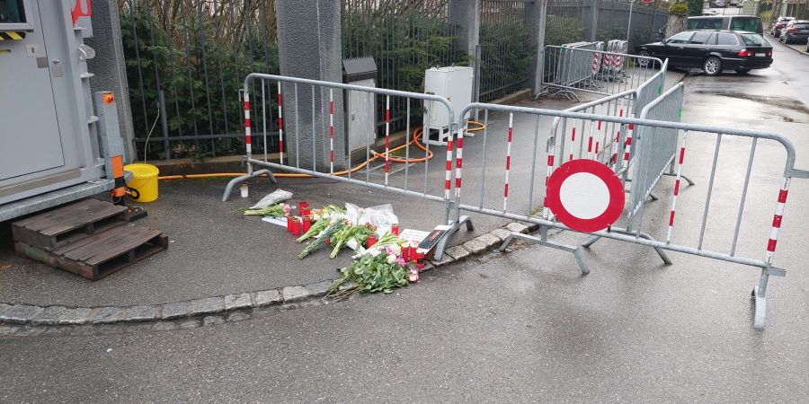 Die Blumen und Kerzen liegen neben dem Polizeihäuschen, das die Botschaft bewacht.