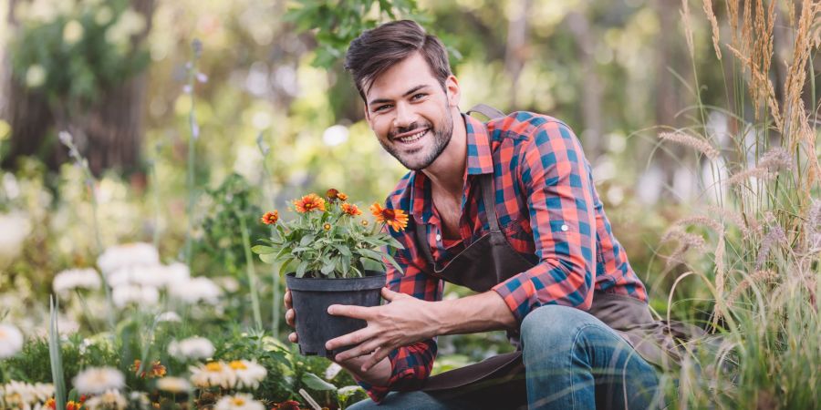 Lächelnder Gärtner mit Blumentopf in der Hand