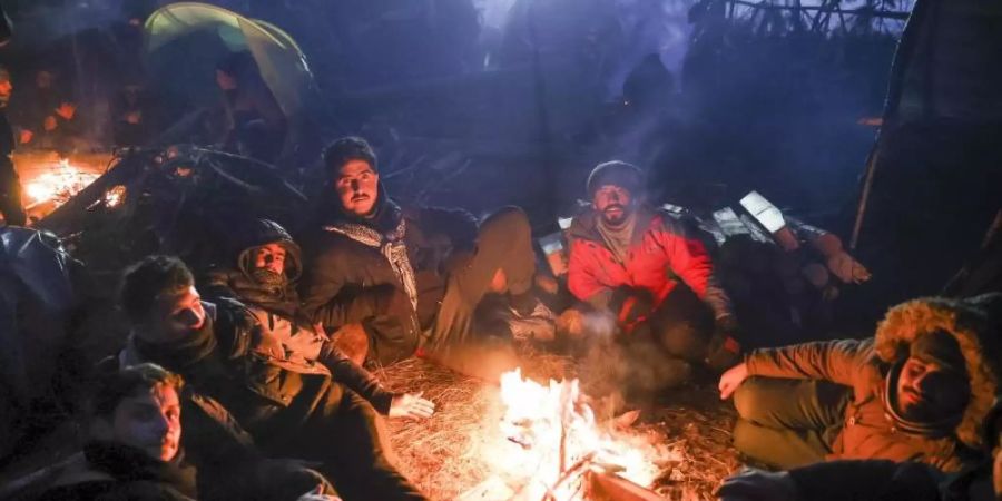 Migranten wärmen sich an einem Feuer an der belarussisch-polnischen Grenze auf. Foto: Oksana Manchuk/BelTA/AP/dpa