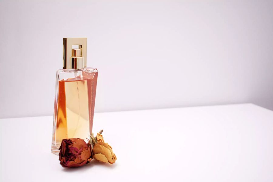 Parfumflasche mit trockener Rose daneben