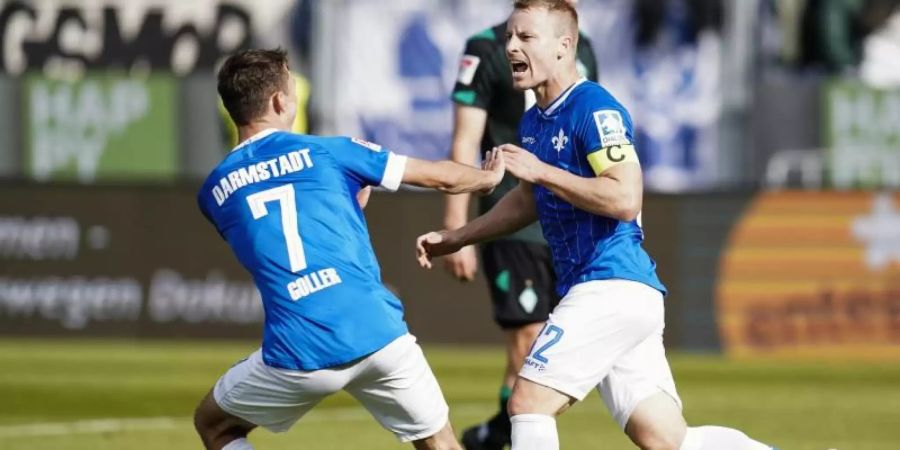 Darmstadts Torschütze Fabian Holland (r) jubelt mit Benjamin Goller über das Tor zum 1:0. Foto: Uwe Anspach/dpa
