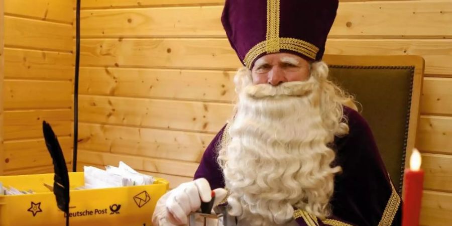 Ein Nikolaus sitzt in seiner Nikolaushütte des Nikolauspostamtes in St. Nikolaus und beantwortet Briefe. Foto: Peter Gerecke/ Festausschuss St. Nikolaus e.V./dpa