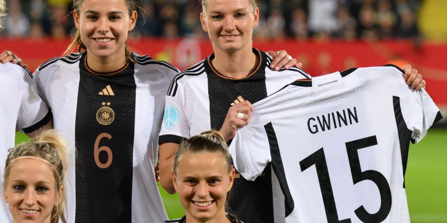 Alexandra Popp hält beim Mannschaftsfoto das Trikot der verletzen Giulia Gwinn in den Händen.