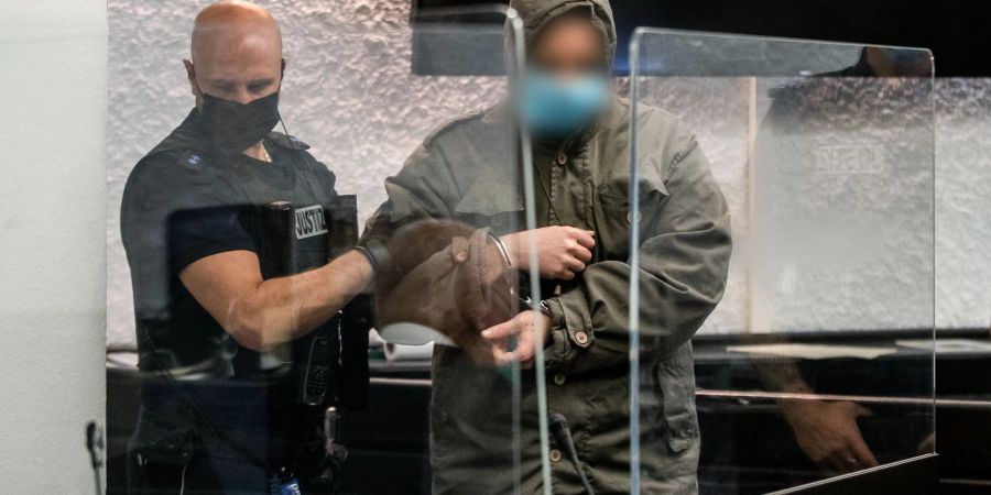 Ein Justizbeamter führt den Angeklagten (r) zu seinem Platz im Gericht.