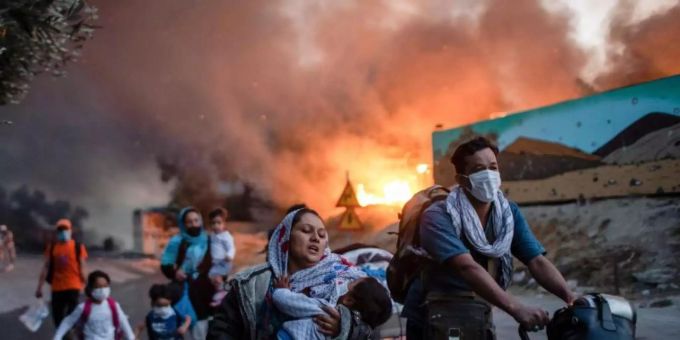 Migranten fliehen vor einem grossen Feuer mit ihren Habseligkeiten aus dem Flüchtlingslager Moria. Foto: Petros Giannakouris/AP/dpa Migranten fliehen vor einem grossen Feuer mit ihren Habseligkeiten aus dem Flüchtlingslager Moria. Foto: Petros Giannakouris/AP/dpa