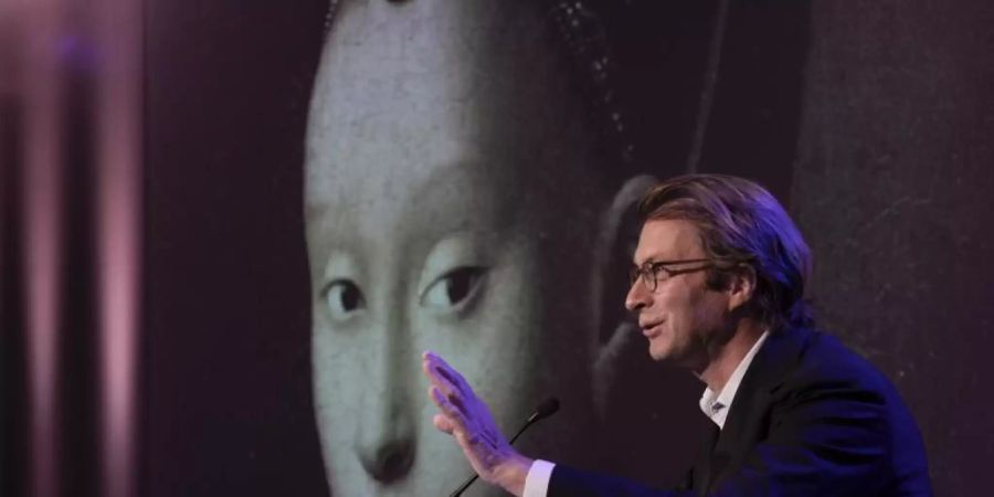 Taco Dibbits, Generaldirektor des Rijksmuseums, spricht über die Ausstellung "Remember Me" (dt: Vergiss mich nicht), während das Porträt einer jungen Frau von Petrus Christus auf die Leinwand projiziert wird. Foto: Peter Dejong/AP/dpa