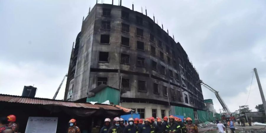 Feuerwehrleute vor dem ausgebrannten Fabrikgebäude in Rupganj