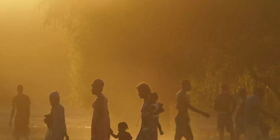 dpatopbilder - Migranten, viele von ihnen aus Haiti, gehen zu einem improvisierten Flüchtlingslager in Ciudad Acuña. Die USA fliegen Haitianer, die in einer texanischen Grenzstadt kampieren, zurück in ihr Heimatland und hindern andere am Grenzübertritt aus Mexiko. Foto: Fernando Llano/AP/dpa