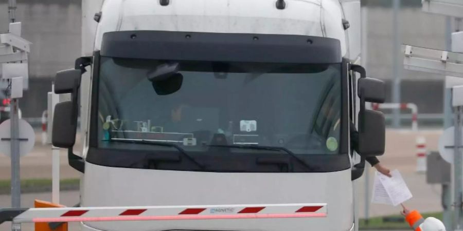 Die Dokumente eines Lastwagenfahrers werden kontrolliert, als der Lkw den Check-in für den Zug durch den Eurotunnel passiert. Foto: Frank Augstein/AP/dpa
