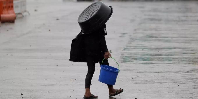 Eine Frau nutzt einen Plastikbehälter, um sich vor dem Regen zu schützen. Taifun vor den Philippinen