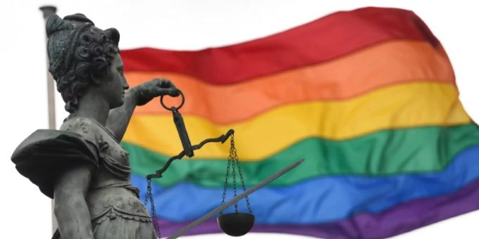 Regenbogenfahne weht neben Justitia-Statue. gleichgeschlechtliche ehe kuba
