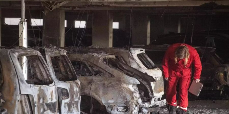 Ein Sachverständiger inspiziert in dem Parkhaus am völlig ausgebrannte Autos. Foto: Bernd Thissen/dpa