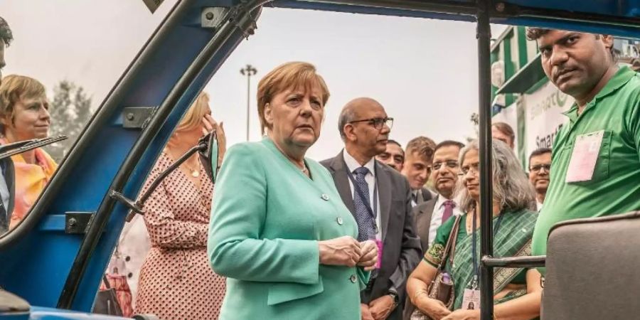 Bundeskanzlerin Angela Merkel (CDU) lässt sich im Rahmen des Besuchs den Betrieb von elektrisch angetriebenen e-Rikschas erklären. Foto: Michael Kappeler/dpa