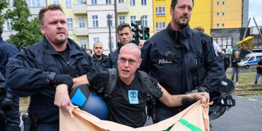 Ein Klimaaktivist der Bewegung "Extinction Rebellion" wird nach einer Strassenblockade der Warschauer Strasse, Berlin, von Polizisten weggetragen. Foto: Christophe Gateau