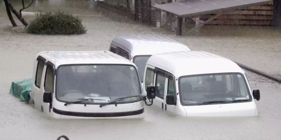 Fahrzeuge stehen in einem überfluteten Wohngebiet in der Präfektur Mie. Foto: ---/kyodo/dpa