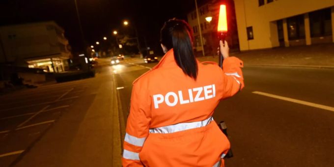 Eine Polizistin weist einen Autolenker an. balzers Landespolizei Liechtenstein Orange
