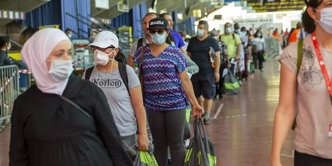 Menschen stehen im Genfer Eisstadion Les Vernets Schlange, um Spendensäcke mit Essen und Hygieneartikeln zu erhalten. Coronavirus