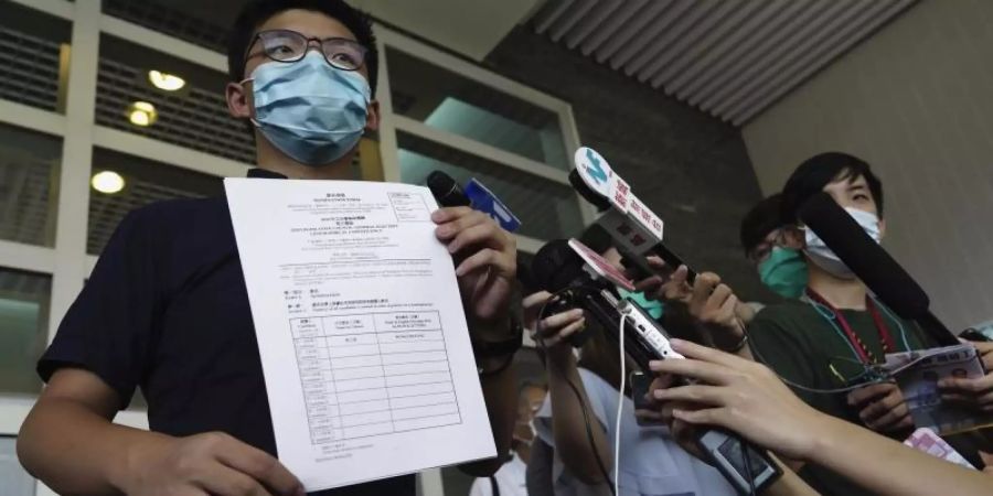 Aktivist Joshua Wong zeigt Journalisten die Nominierungsunterlagen für die Parlamentswahl im September. Foto: Vincent Yu/AP/dpa