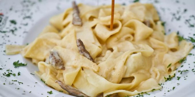Pappardelle mit Pilzen in Rahmsauce. Breite Nudeln