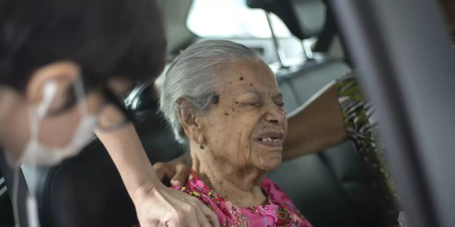 Maria de Lourdes (101) verzerrt das Gesicht, während sie eine Dosis des chinesischen Impfstoffs Sinovac Biotech COVID-19 an einer Drive-Thru-Impfstelle im Sambadrome erhält. Foto: Bruna Prado/AP/dpa