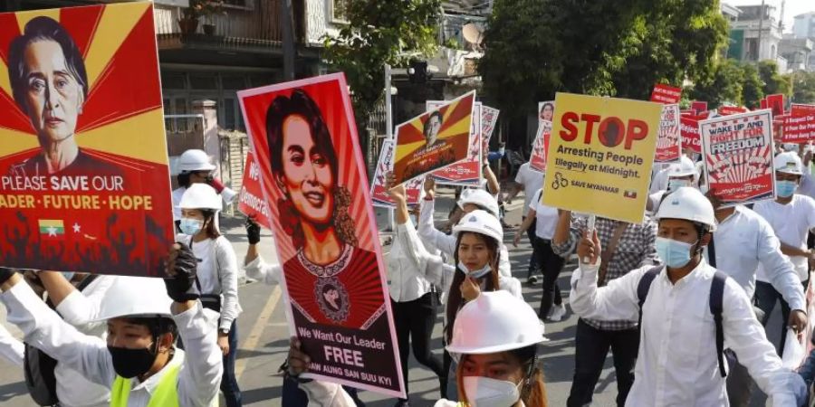 Menschen halten in Mandalay Plakate mit Bilder der abgesetzten Regierungschefin Aung San Suu Kyi, während sie gegen den Militärputsch protestieren. Foto: Uncredited/AP/dpa