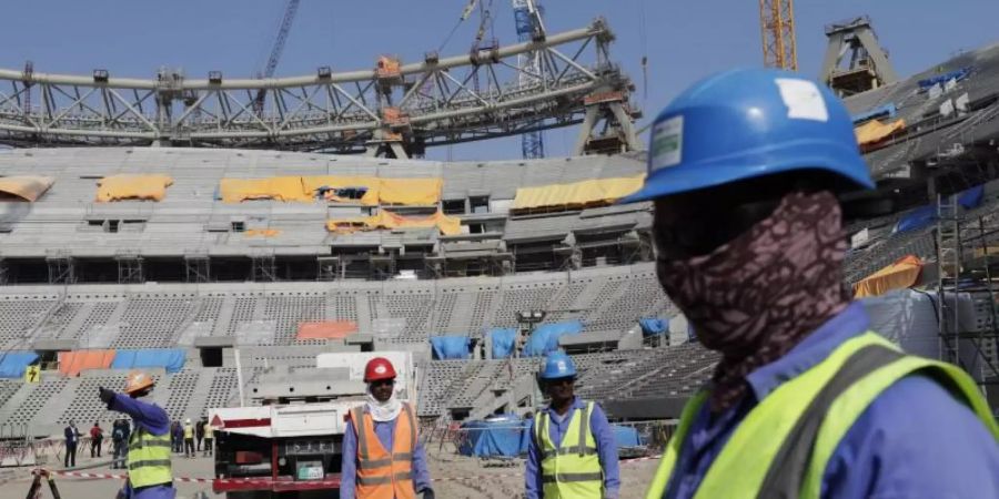 Bauarbeiter arbeiten am Lusail-Stadion, einem der Stadien der WM 2022. Foto: Hassan Ammar/AP/dpa/Archivbild