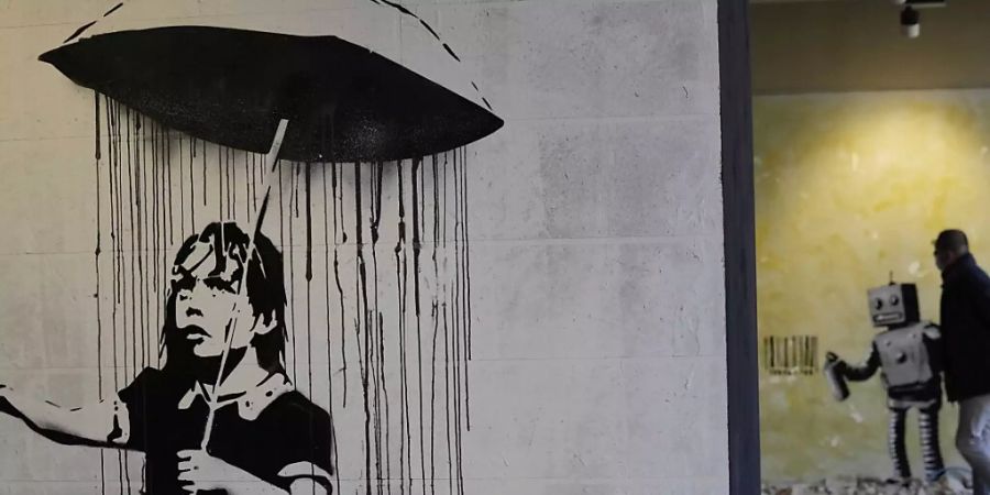 «The Umbrella girl», eine Reproduktion eines Wandgemäldes des britischen Künstlers Banksy. Foto: Luca Bruno/AP/dpa - ACHTUNG: Nur zur redaktionellen Verwendung und nur mit vollständiger Nennung des vorstehenden Credits